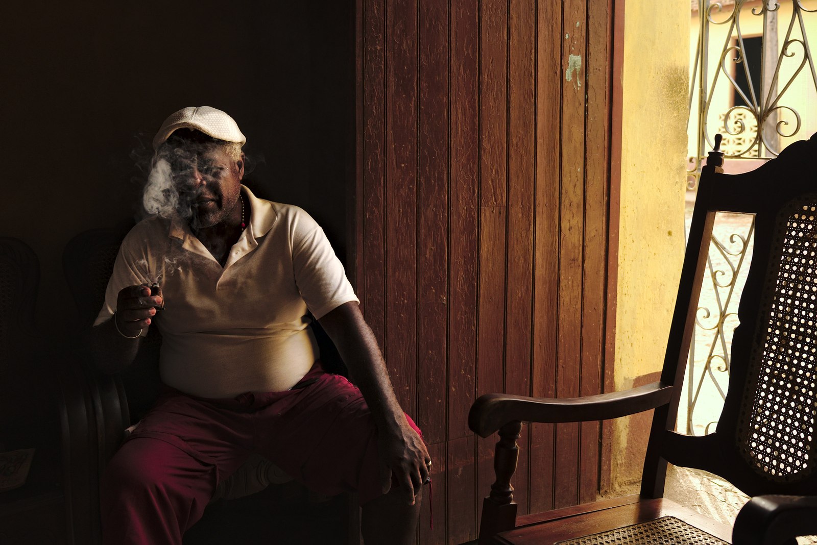 Man smoking a cigar inside his house in Trinidad.